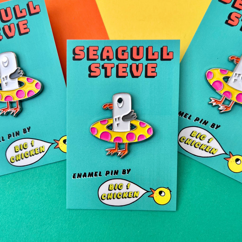 Seagull Steve soft enamel pin. He is lovely and bright and his colours are white, grey with an orange beak and feet. He has a yellow rubber ring with bright pink dots. He has a silver line around him. On back there is a yellow rubber fastener. He comes on a little big 1 chicken card with his name on it. He is approximately 3cm tall.