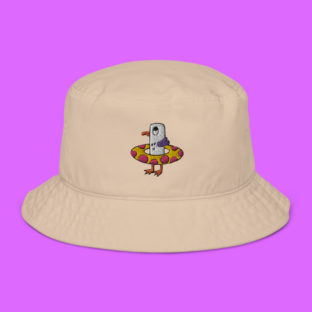 Seagull Steve 100% organic cotton bucket hat in a stone colour. Seagull Steve is embroidered on the hat in purple/grey, pink, white, yellow, orange and black. Seagull Steve is on the front of the hat in the middle.