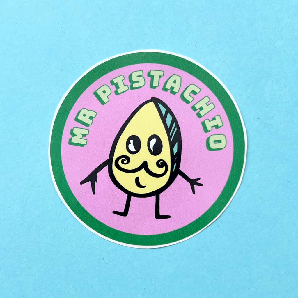 Mr Pistachio round vinyl sticker. Mr Pistachio is a cute little character with a moustache and a smile. He is pale green and yellow. The background of this sticker is pink. The sticker is approximately 88mm in width and is also water resistant.